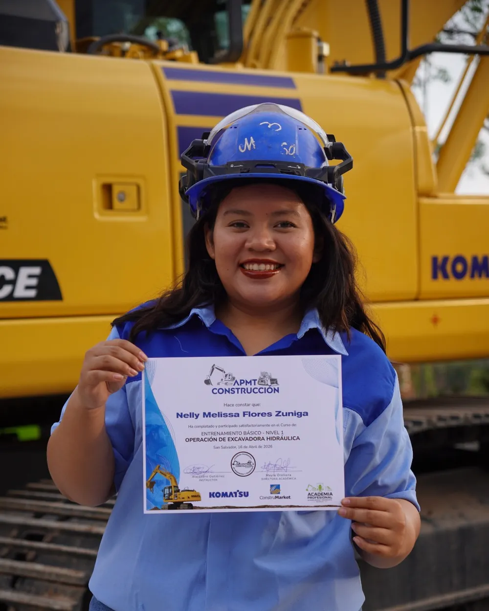 Nelly Melissa Flores Zuniga con su certificado frente a la excavadora en la que hizo su práctica