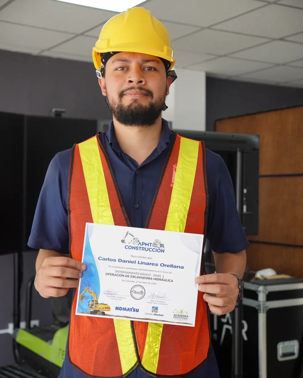 Carlos Daniel Linares Orellana con casco y su certificado en la sala de simuladores